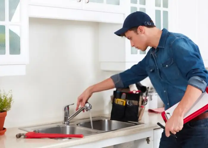 A contractor potentially sent by ICAN Services to fix a sink faucet in a homeowners kitchen