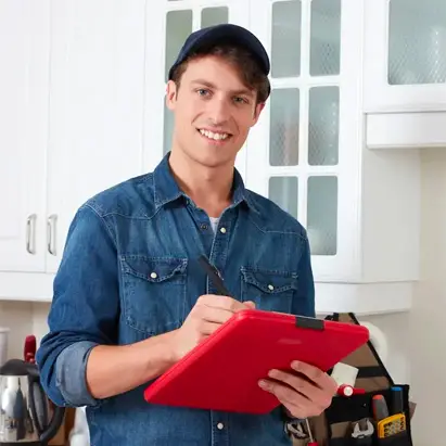 A possible ICAN Services partnered contractor man standing in a kitchen holding a red clipboard